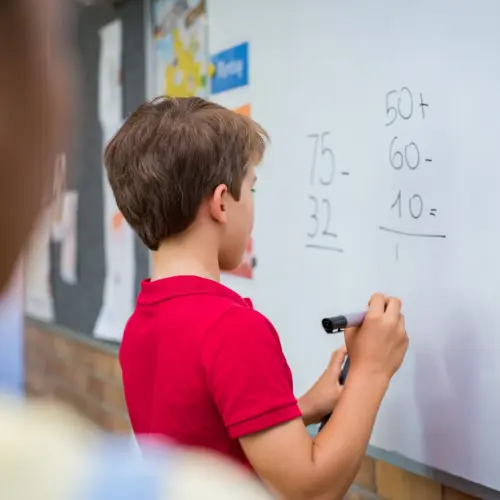 a boy writing on a white board